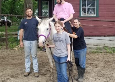 Man with helmet on being assisted on horse.